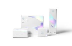 three boxes with holographic designs on the front and back, one is white