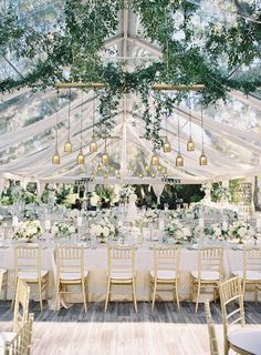 an outdoor tent with tables, chairs and chandeliers