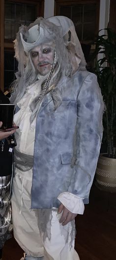 a man dressed up as a zombie holding a cell phone and wearing a plastic suit