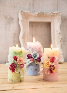 three candles with flowers on them sitting on a table