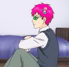 a man with pink hair and glasses sitting on a bed