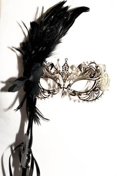 This is gorgeous gold masquerade mask that I just added to the large variety of different designs of metal masks and lace embroidered masks. This mask is a metal gold mask decorated with shimmered white rhinestones to enhance the design of the mask and the facial features This mask has a mask handle and decorated with a black flower and gorgeous black rooster feathers! I hope you love this mask! If you wish this mask to be without a stick please feel free to leave a note in the order that you wi Gold Gothic Masquerade Mask For Carnival, Gothic Gold Masquerade Mask For Carnival, Gold Gothic Masquerade Mask For Party, Elegant Feathered Masquerade Mask For Mardi Gras, Elegant Feathered Masquerade Mask, Elegant Feathered Eye Mask For Masquerade, Elegant Eye Mask For Theater, Elegant Theater Eye Mask, Elegant Mardi Gras Masquerade Eye Mask