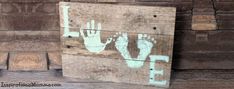 a hand and foot print painted on a wooden box next to a brick wall with the word love written in white