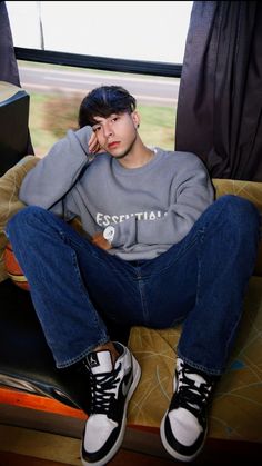 a young man sitting on top of a couch next to a window