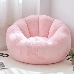 a pink bean bag chair sitting on top of a white floor next to a window