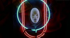 a woman's face is reflected in a circular neon frame on a black background