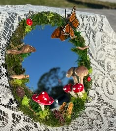 a close up of a mirror with mushrooms and butterflies on it's side,