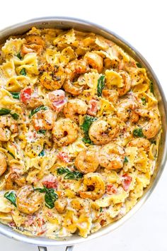 pasta with shrimp and spinach in a pan on a white table top, ready to be eaten