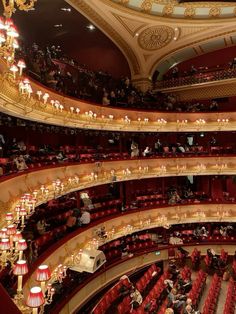 an auditorium filled with red seats and chandeliers