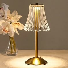 a lamp that is on top of a table next to some flowers in a vase