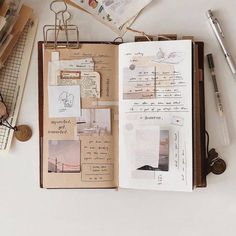 an open book with papers and pens on it next to some other items that are sitting on the table