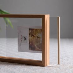 a wooden frame with a photo in it on a table next to a potted plant