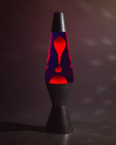 a black table with a red and blue vase sitting on it's side in front of a dark background