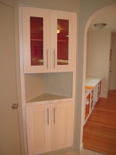 an empty kitchen with white cabinets and wood floors