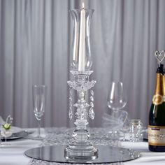 a glass candle holder on top of a table next to a bottle of wine and glasses