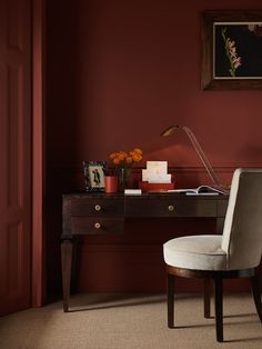 a chair sitting in front of a desk with a lamp and flowers on top of it