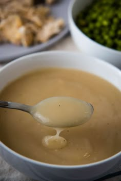 a spoon full of soup with broccoli and other foods in bowls behind it