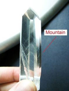 a person is holding a crystal object with the word mountain in it's center