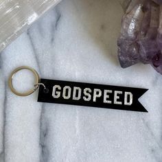 a keychain with the word god speed on it sitting next to some crystals