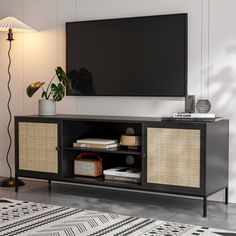 a flat screen tv sitting on top of a wooden entertainment center next to a lamp