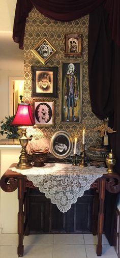 a dining room table with pictures on the wall above it and candles in front of them