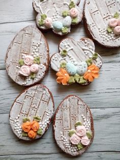 several decorated cookies sitting on top of a wooden table with frosting and flowers around them