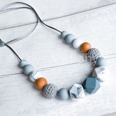 a necklace made out of beads and wood on a white wooden table with a gray cord