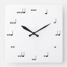 a white square clock with musical notes on the face and numbers in black, against a white background