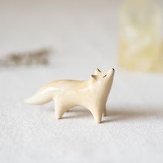 a small white fox figurine sitting on top of a table next to a chain