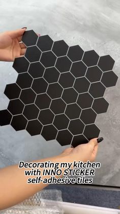 someone is holding up a black hexagonal tile