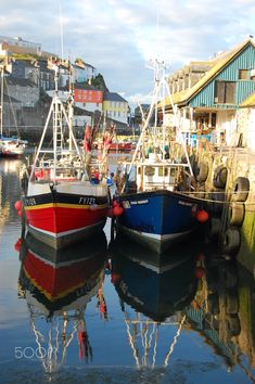 two boats are docked in the water next to some buildings