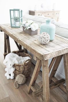 a wooden table topped with vases next to a white bed in a living room