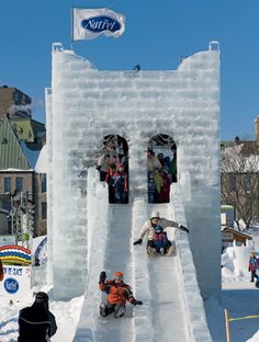 several people are sitting on an ice castle in the middle of town, while others watch