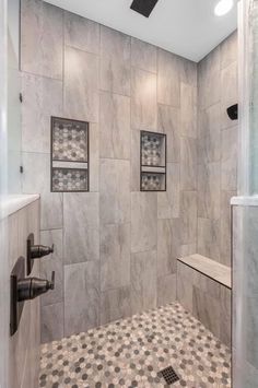 a walk in shower sitting next to a tiled wall and floor with pictures on the walls