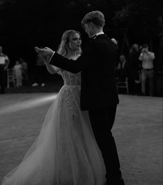 a bride and groom are dancing together at their wedding reception in black and white photo