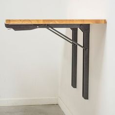 a wooden table sitting on top of a metal shelf next to a white wall and floor