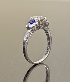 DeKara Designs Collection Beautiful Modern/Art Deco Diamond Blue Sapphire Pave Set Engagement Ring. Metal- 90% Platinum, 10% Iridium. Stones- 1 Genuine Round Diamond K-L Color VS1-VS2 Clarity 1.01 Carats, 96 Round Diamonds H-I Color SI1 Clarity 0.52 Carats, 2 Special Cut Trapezoid Blue Sapphires 0.40 Carats. Size- 6 1/2. FREE SIZING A Jaw Drop Gorgeous Art Deco Inspired Round Diamond Center Special Cut Blue Sapphire Diamond Engagement Ring Handmade in Platinum. There is a beautiful expertly pron Diamond White Brilliant Cut Sapphire Wedding Ring, Diamond White Sapphire Ring With Brilliant Cut For Wedding, Diamond White Brilliant Cut Sapphire Ring For Wedding, Exquisite Sapphire Ring With Brilliant Cut For Wedding, Wedding Sapphire Ring In Diamond White With Brilliant Cut, Fine Jewelry Wedding Halo Ring With Center Stone, Wedding Halo Ring With Center Stone Fine Jewelry, Fine Jewelry Halo Ring With Center Stone For Wedding, Sapphire Cluster Ring For Promise