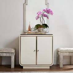 a white cabinet sitting next to a mirror on top of a wooden floor covered in flowers