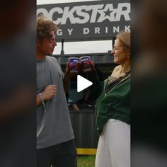 a man and woman standing next to each other in front of a sign that reads rockstar energy drink