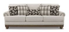 a white couch with pillows on it and some brown and white throw pillows in the back