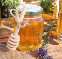 honey and lavender flowers sit on a wooden table with jars full of honey in the background