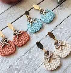 four pairs of earrings with bows on them sitting on top of a white wooden table