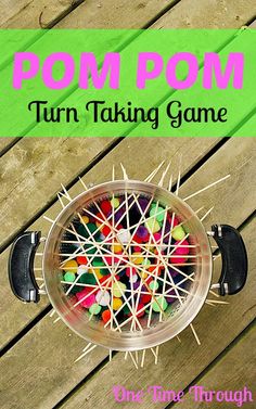 a bowl filled with pins and sticks sitting on top of a wooden table next to the words pom pom turn talking game