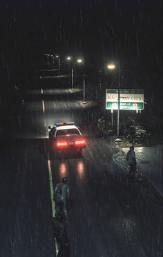 a police car driving down a rain soaked street next to a person with an umbrella