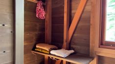 the inside of a wooden cabin with shelves and towels on it's sides, next to a window