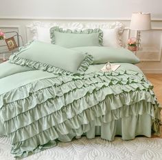 a bed with green ruffled sheets and pillows