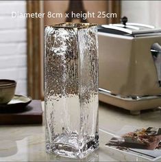 a tall glass vase sitting on top of a counter next to a toaster oven