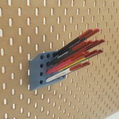 three pencils are placed in a holder on a pegboard with holes and dots