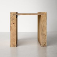 a wooden table sitting on top of a cement floor next to a white wall in an empty room