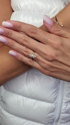 a woman in a white dress holding her wedding ring on her left hand and wearing a pink manicure